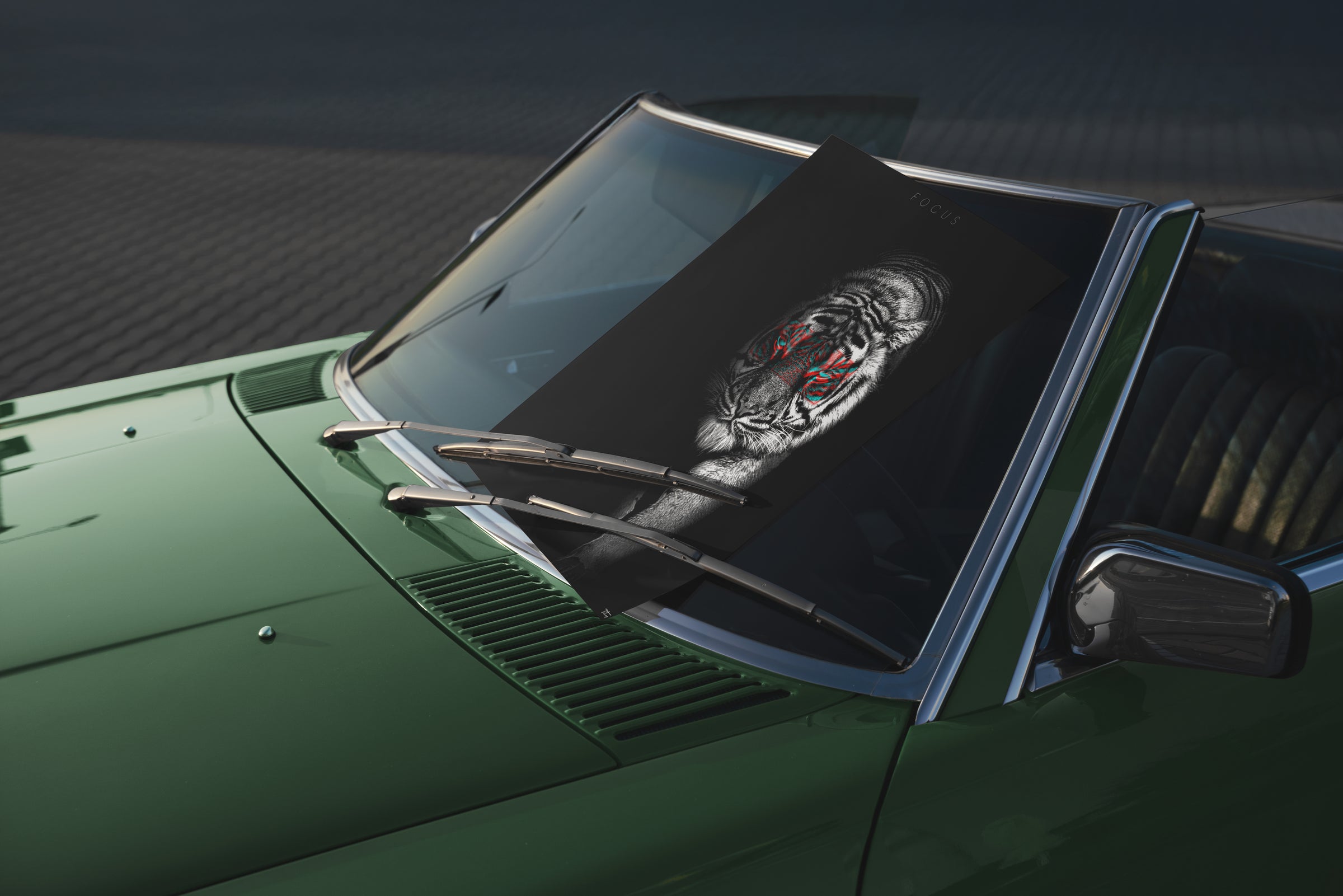 Fine art print with a highly detailed black and white tiger design featuring red highlights, placed on the windshield of a green vintage car.